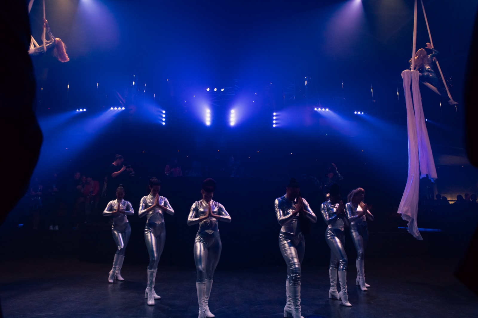 Performers in silver under stage light