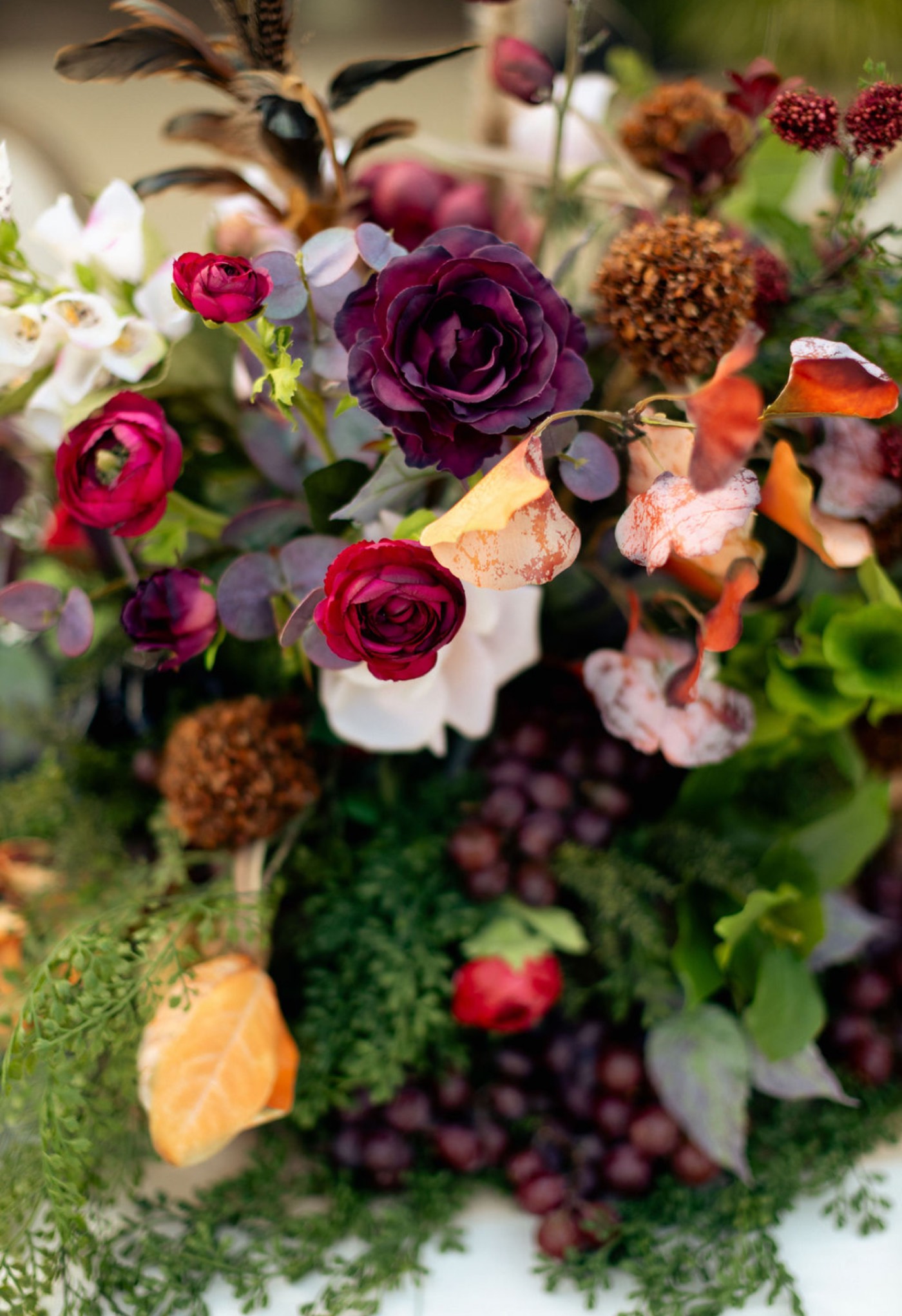 Floral arrangement with grapes and feathers