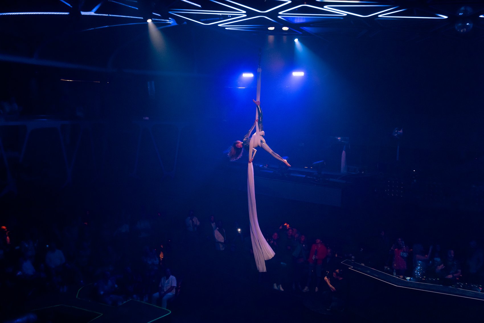 An aerialist on silks above the crowd