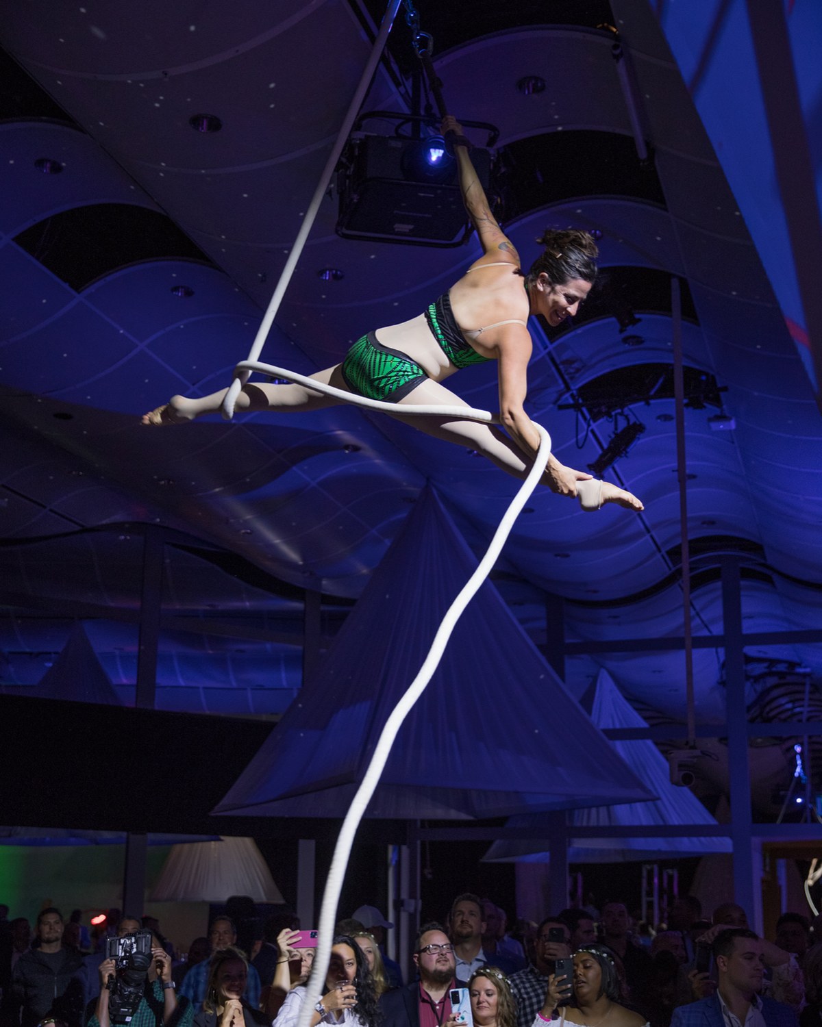 An aerialist suspended on a white apparatus